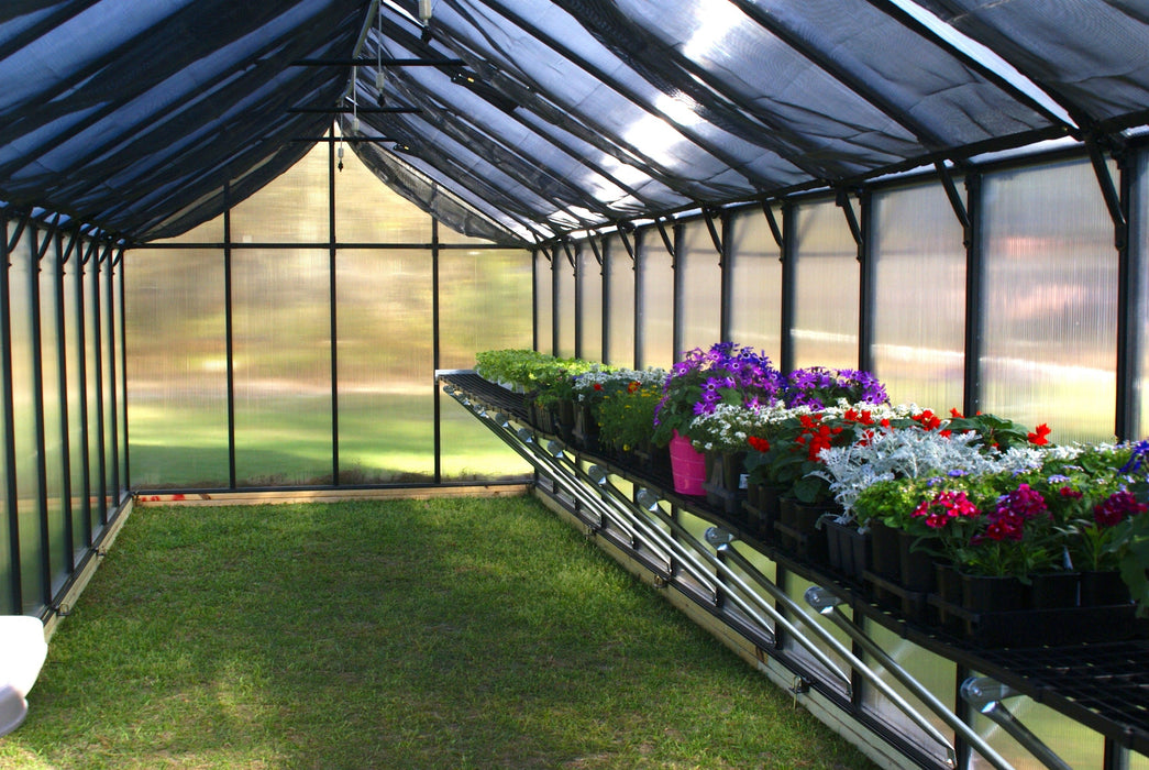 Interior of Riverstone MONT Greenhouse Premium 24ft model with bench shelving and flowering plants inside structure