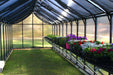 Interior of Riverstone MONT Greenhouse Premium 24ft model with bench shelving and flowering plants inside structure