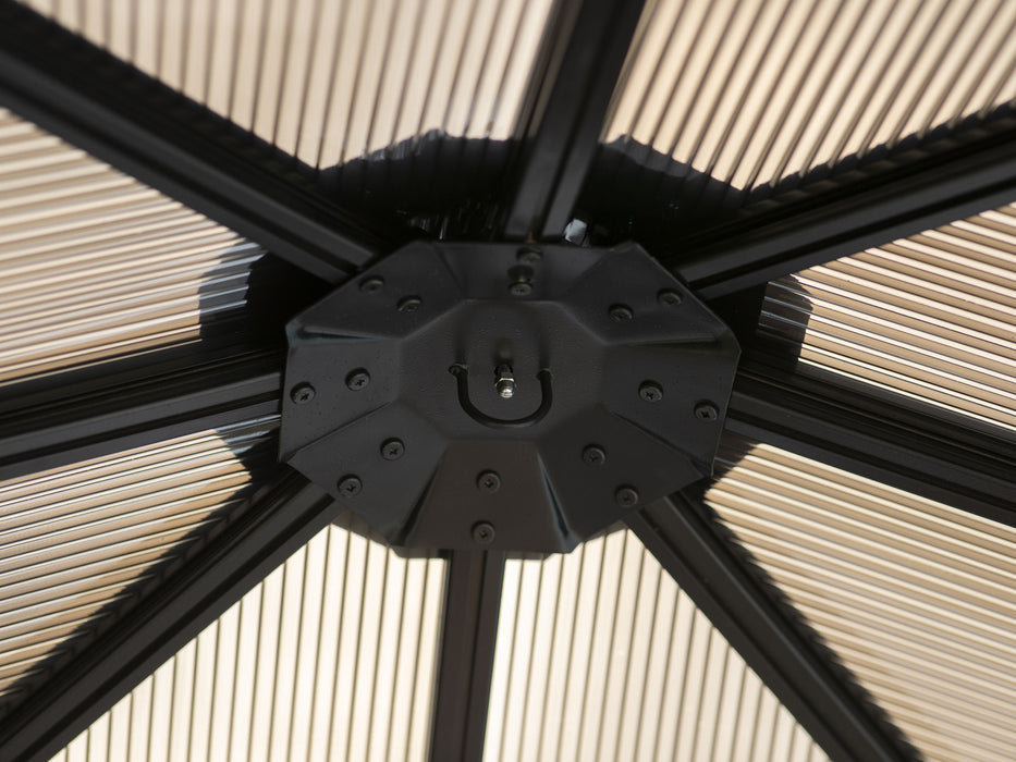 Close-up view of the central hub of a 10x10 Venus Gazebo roof showing a black structure with multiple beams converging and beige privacy curtains hanging in the background.