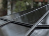 Slightly angled view of a 10x10 Venus Gazebo roof exterior showing the black metal frame and the semi-transparent, corrugated roof panels.