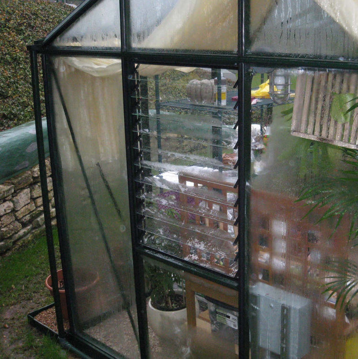 Close-up of Royal Victorian VI 34 Greenhouse featuring a louvre window for ventilation, with moisture on glass panels.
