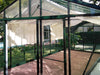 View inside Exaco Janssens Royal Victorian VI 46 greenhouse showing louvre window ventilation, roof curtains, and clear tempered glass walls.

