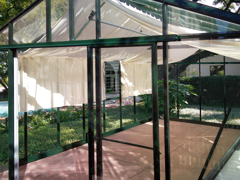 View inside Exaco Janssens Royal Victorian VI 46 greenhouse showing louvre window ventilation, roof curtains, and clear tempered glass walls.

