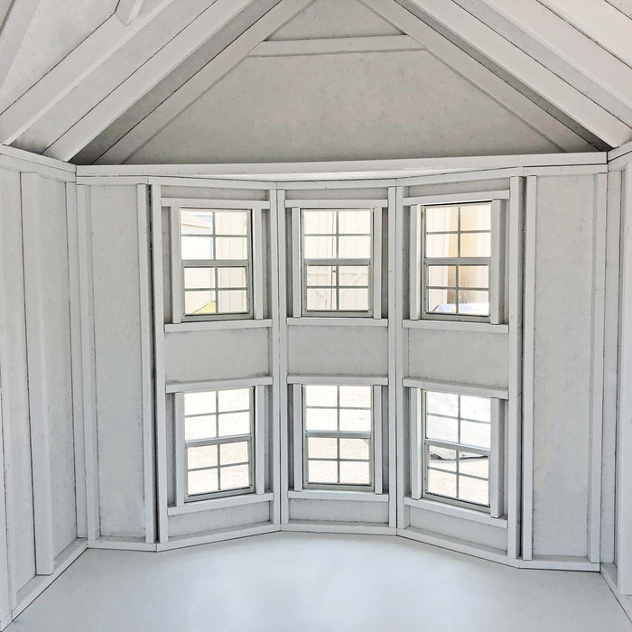 Interior view of Sara’s Victorian Mansion playhouse from Little Cottage Co., showing tall bay windows and vaulted ceiling in bright white finish