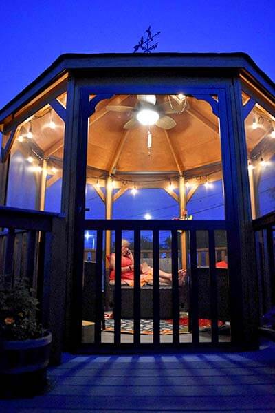 12 Foot Wood Gazebo-In-A-Box with Floor screened with ceiling fan and chair inside
