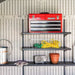 Close-up of the Lifetime storage shed's interior shelving with a tool chest, watering can, and gloves.