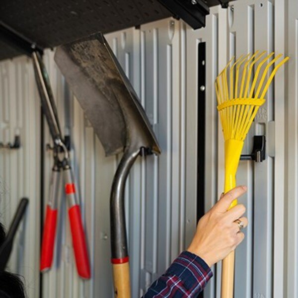 Close-up of the Lifetime storage shed's interior wall hooks holding a shovel, shears, and rake.