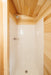 Shower area in the Oasis Tiny Estates Firestack Cabin, featuring a wood-paneled ceiling and white shower enclosure