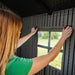Interior view of a woman installing the Lifetime storage shed's window frame.