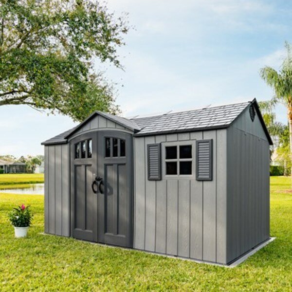 Lifetime side entry storage shed installed by a lake with palm trees, alternate front angle, closed doors.