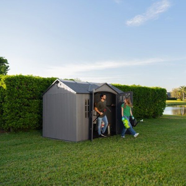 Man and woman at the open door of the Lifetime side entry storage shed, lake and hedges in the background.