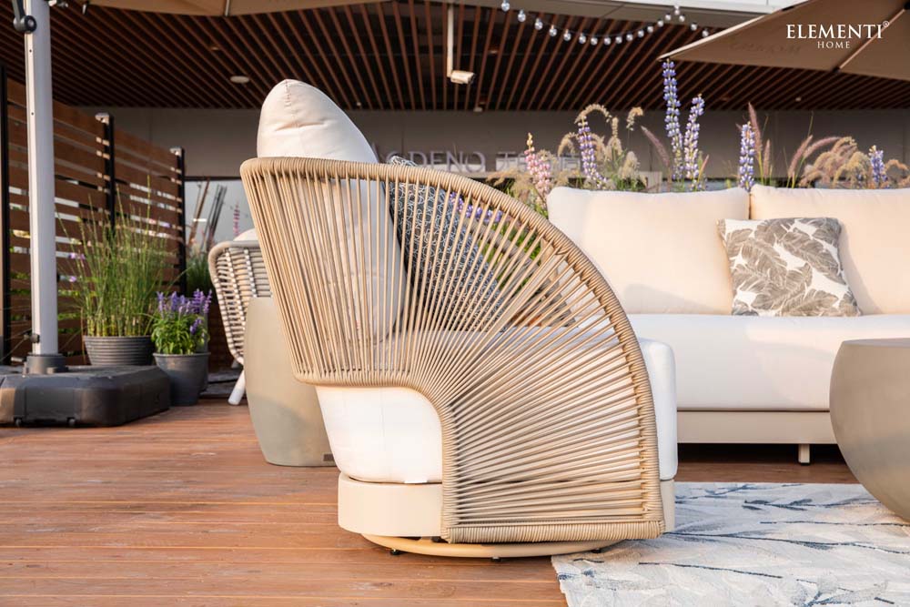 Side profile of Malibu Collection lounge chair from Elementi Outdoor Furnitures, showing its curved woven rope frame and plush white cushion detailing.