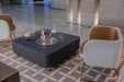 Elementi Perth Ethanol Fire Table in slate black shown in a modern room setting with white chairs and coffee cups
