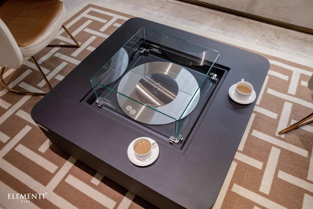 Slate black Elementi Perth Ethanol Fire Table with glass guard and two coffee cups on a patterned rug