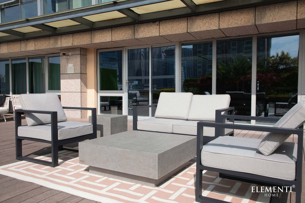 A sleek and modern balcony setup with the Elementi Tevere Series Square Coffee Table in Space Grey, accompanied by contemporary seating on a geometric rug.