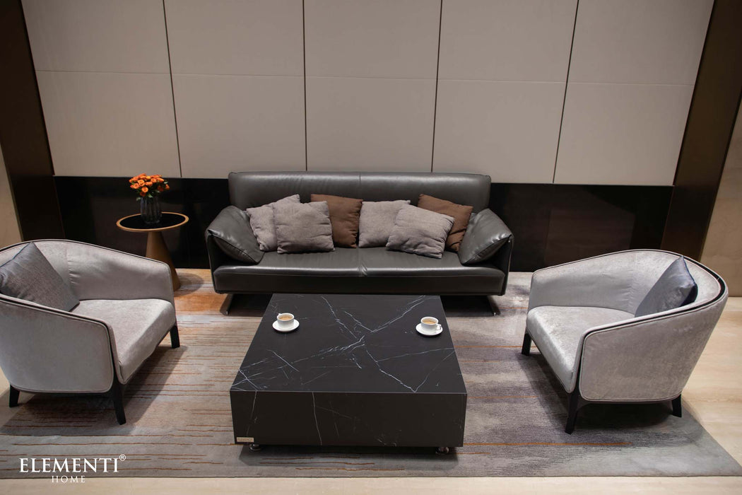 Elegant living room setting with the Elementi Marble Porcelain Series Square Medium Coffee Table in Bulgaria Black, alongside a sofa, armchairs, and decorative flowers.