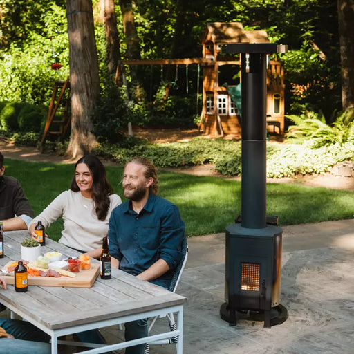People enjoying the warmth of a Solo Stove Tower patio heater in a cozy backyard setting.