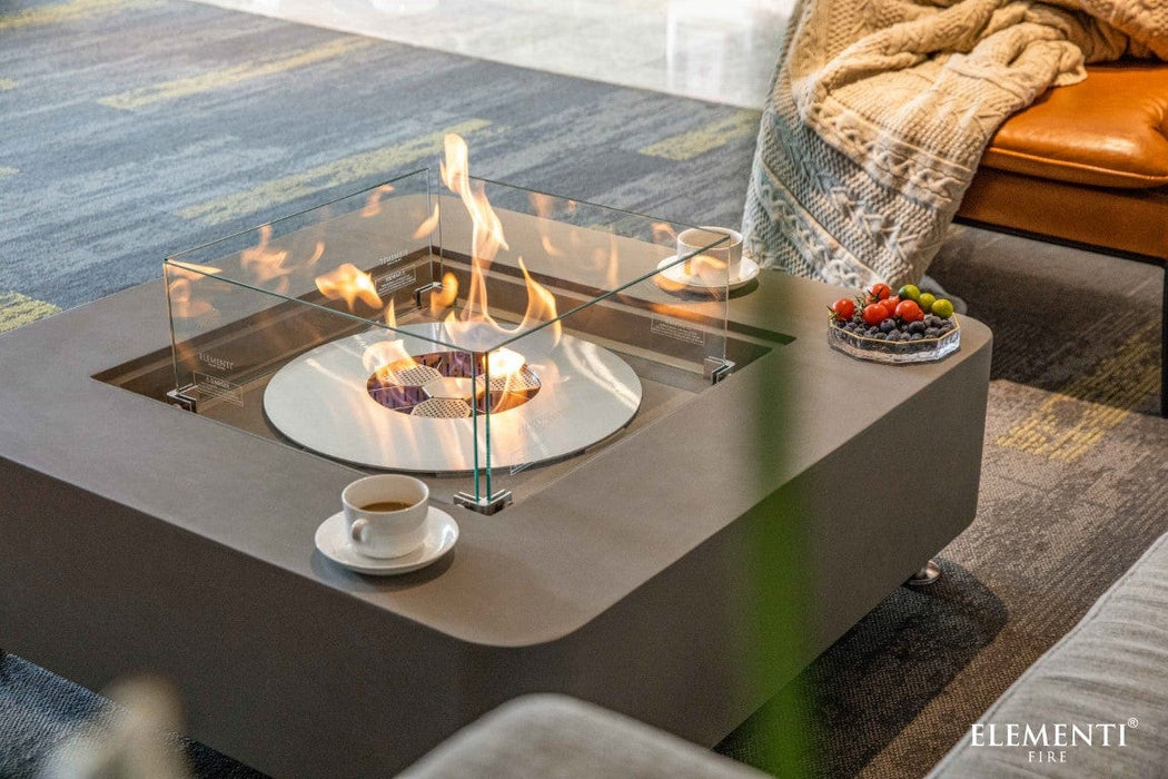 Elementi Perth Ethanol Fire Table in space grey with flames lit, surrounded by fruit and coffee cups