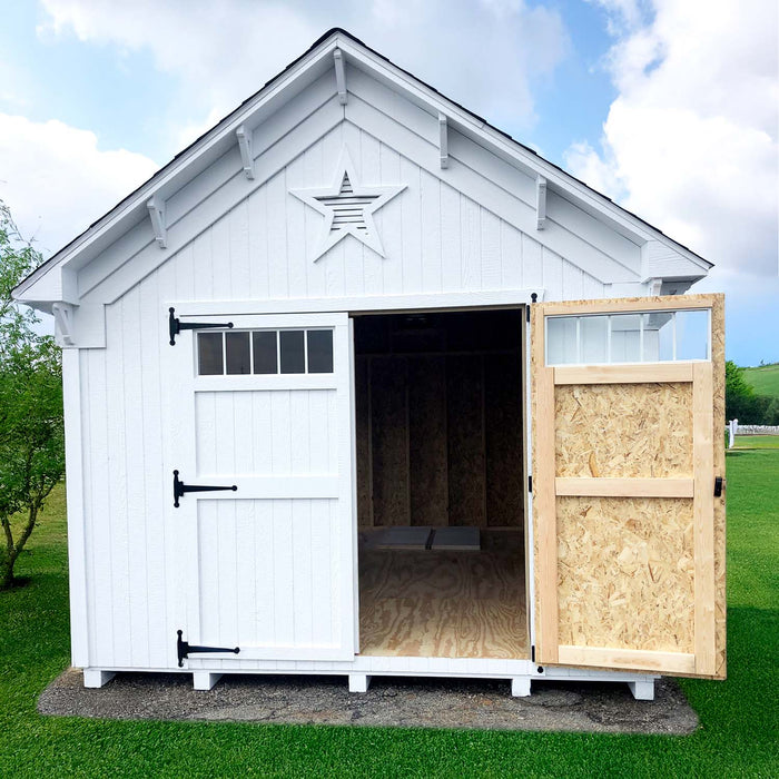 Front view of Little Cottage Co. Star Barn with one door open revealing wood interior, star vent detail, and white exterior siding.