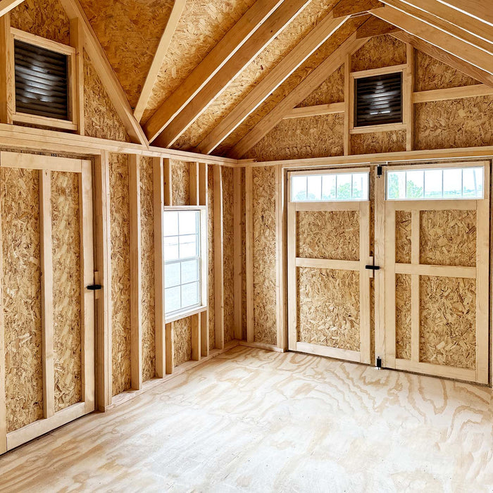 Inside view of the Little Cottage Co. Star Barn featuring double doors, side windows, high rafters, and bright natural wood finish.