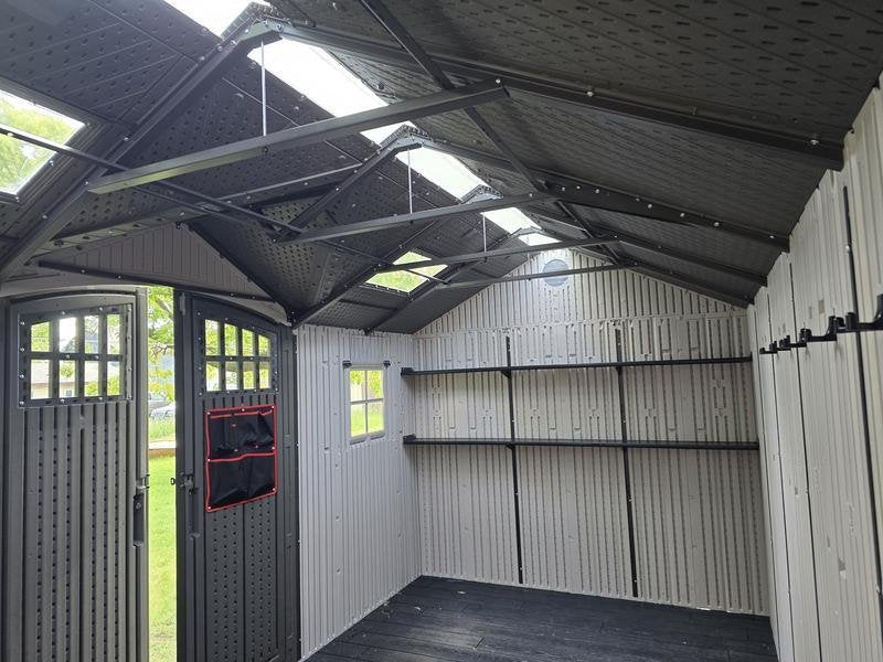 Interior view of the Lifetime 15x8 ft. storage shed showing the roof trusses, skylights, and empty shelving.