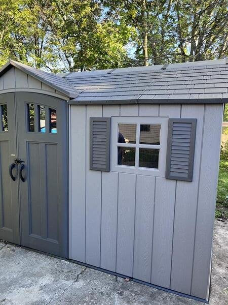 Exterior close-up of the Lifetime storage shed's side entry door and window with decorative shutters.