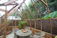 Stylish interior seating arrangement in the Alton Cambridge Cedar Greenhouse with lush greenery.