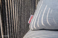 Detailed view of Sunbrella fabric label on Elementi Capri Collection outdoor cushion, highlighting durable fabric and intricate woven rope backing.