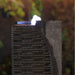 Close up of Yang water fountain corner showing layered stone texture, water flow detail and illuminated top feature at night.