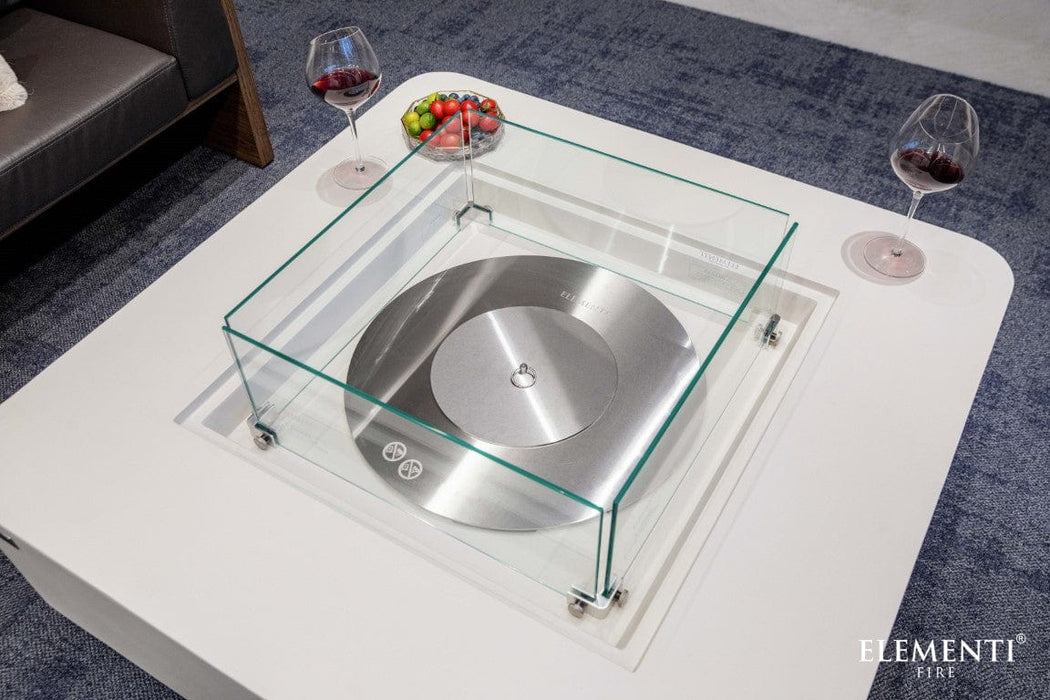 Glass wind guard protecting the burner on the Elementi Perth Ethanol Fire Table with drinks and fruit on the side