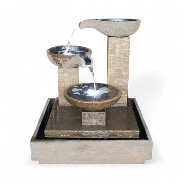 A rustic-finished Trio Bowl Fountain with integrated LED lights illuminating the cascading water.