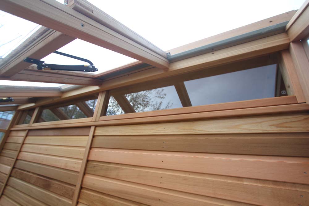 Close-up of the upper ventilation windows of the Alton Cedar Fusion Greenhouse, emphasizing the wood and glass structure.