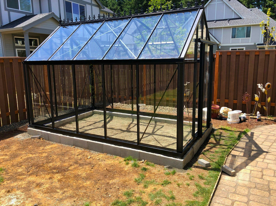 Spacious Exaco Janssens Royal Victorian VI 23 greenhouse positioned on a residential property with a decorative fence and gravel base.