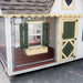 Front exterior of Little Cottage Co. Victorian Cozy Kennel featuring green Dutch door, windows with shutters, and flower boxes
