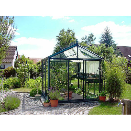 Elegant Exaco Janssens Victorian-style greenhouse VI 23 set in a tranquil garden with a cobblestone path and lush greenery.