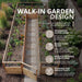Aerial view of the walk-in Garden in a Box 8 x 16 with Greenhouse, showing a stone paver path, 30-inch access door and surrounding cedar raised beds.