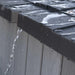 Close-up of rainwater streaming off the dark weather-resistant roof edge of the Lifetime Farmhouse Shed 60542, with wood-grain gray wall panels visible below