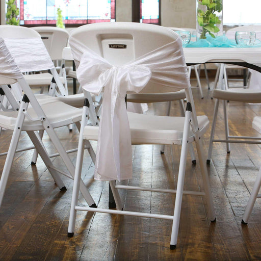 Lifetime 4 Pack White Classic Folding Chair decorated with white sash at wedding reception table