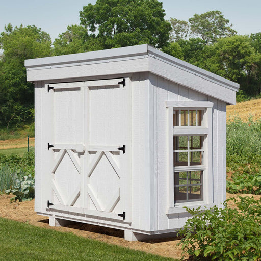 Exterior of Petite Greenhouse from Little Cottage Co., painted white with barn-style doors, side windows, and slanted roof for backyard gardens