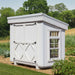 Exterior of Petite Greenhouse from Little Cottage Co., painted white with barn-style doors, side windows, and slanted roof for backyard gardens