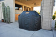 Outdoor view of the Wildfire Ranch Pro grill cart covered with a durable black cover featuring the Wildfire logo