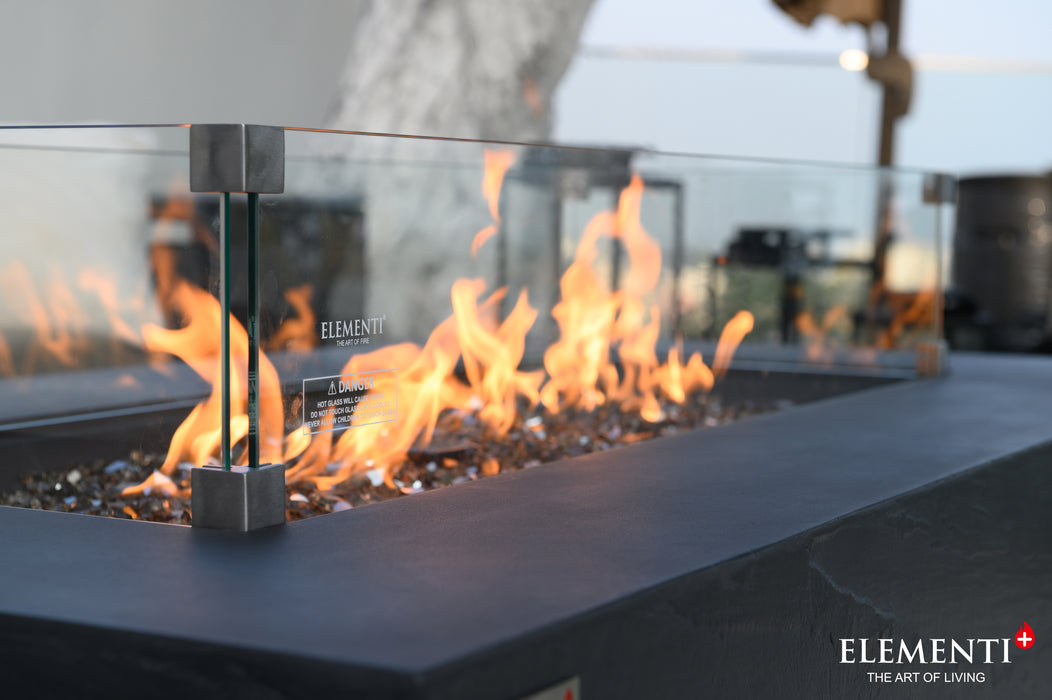 Side view of Elementi Plus Rectangular Wind Screen OFG410/415-WS with flames, showcasing the sleek glass design and sturdy supports.