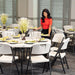 Woman placing a plate on a Lifetime round table set with formal place settings in an event room.