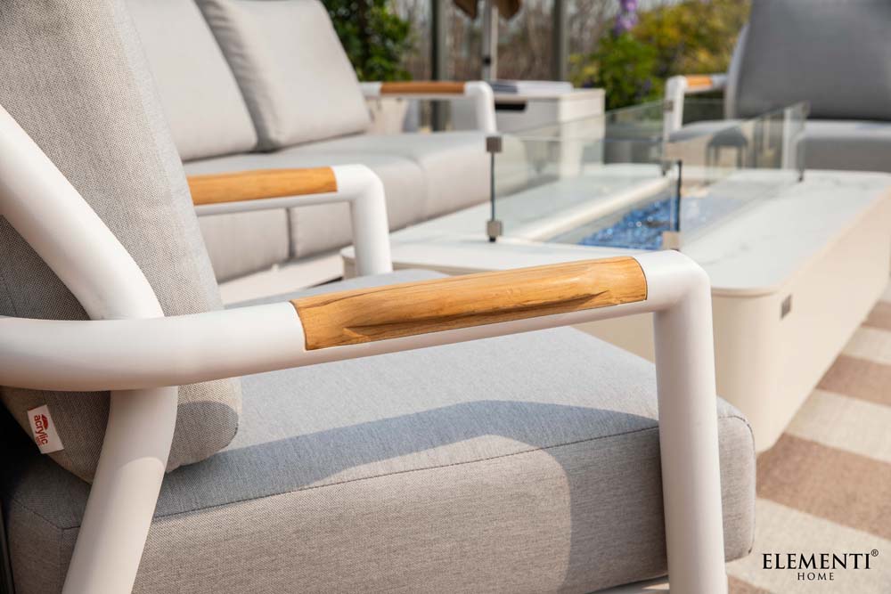 A close-up view of the light brown wooden armrest on a white-framed Elementi Outdoor Furniture piece from the Santorini Collection.