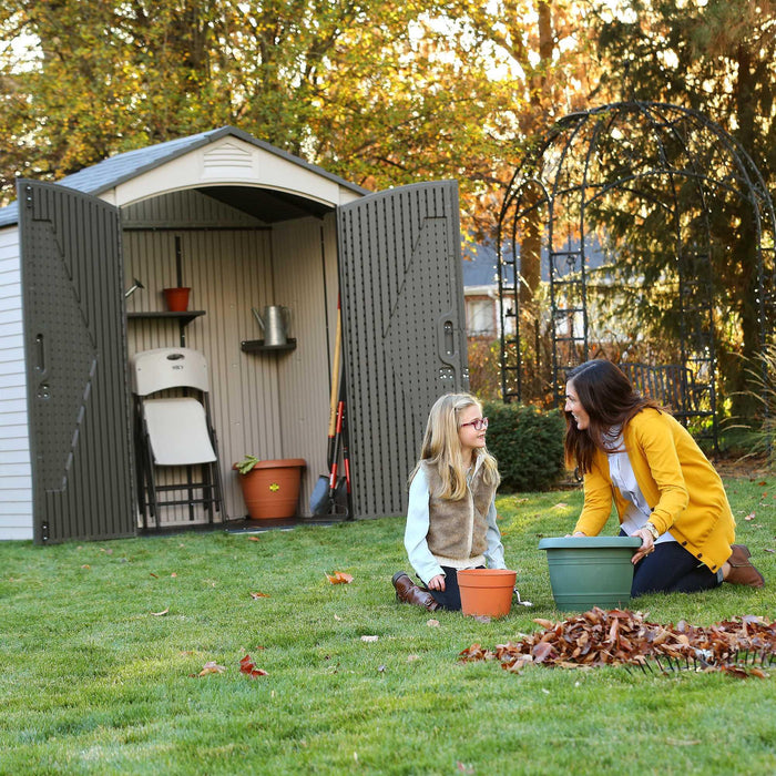 A woman and a girl sitting in front of an open shed displaying equipment inside