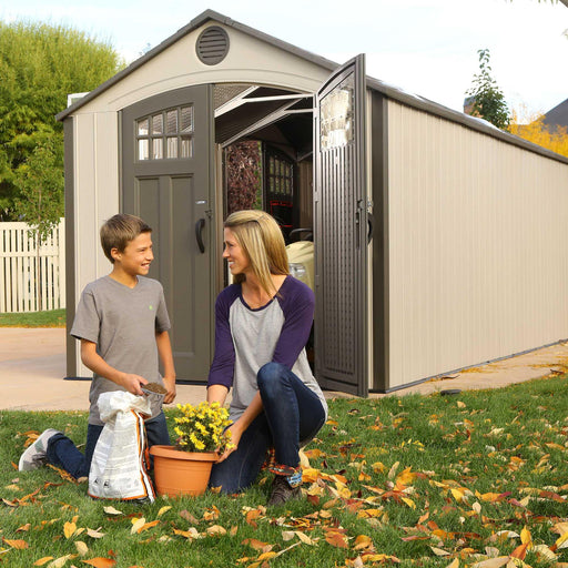 A woman and a boy interacting in front of a Outdoor Storage Shed 
