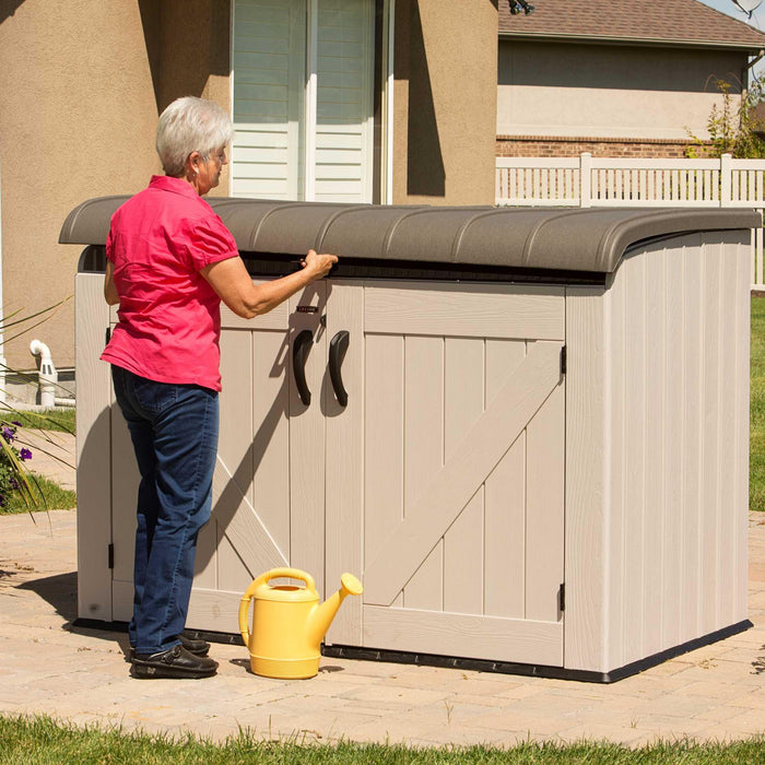 A woman putting a Lifetime Horizontal Storage Shed (75 Cubic Feet) - 60170 into a storage shed.