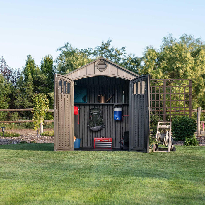 Front view of a storage shed featuring open doors in a grassy yard.