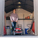 A man standing inside a storage shed with equipment