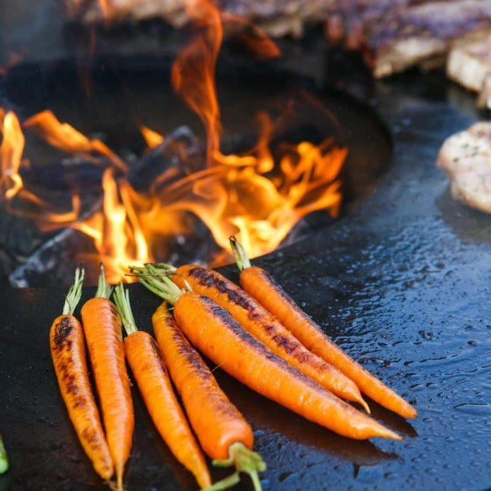 Searing carrots on the Arteflame Classic 40" Grill's spacious cooktop with a fire in the center.